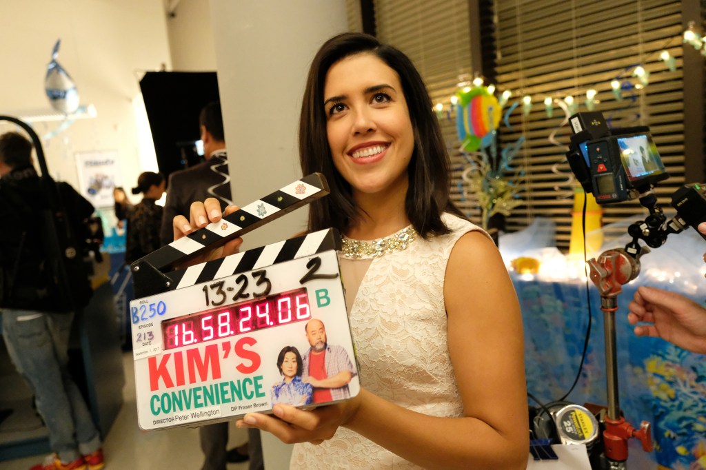 Cast member Nicole Power on set holding a clapperboard